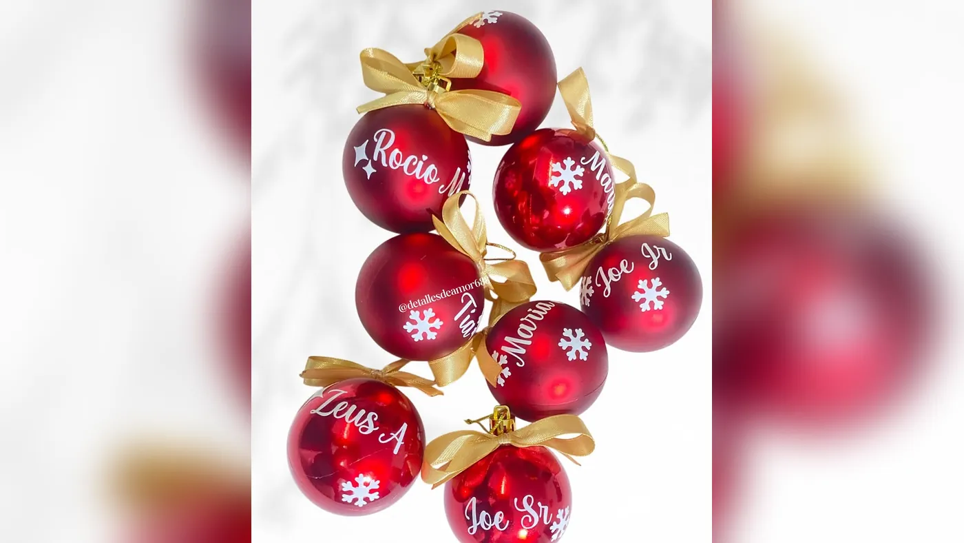 Ocho bolas de Navidad rojas personalizadas con nombres en letra blanca, copos de nieve y moños dorados, Detalles de Amor Medellín