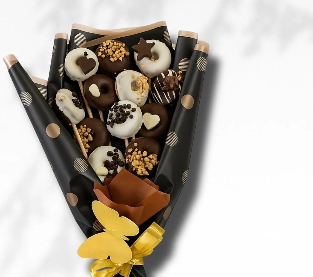 Bouquet of mini donuts dipped in white and dark chocolate, wrapped in black paper with gold dots and a yellow ribbon, Detalles de Amor Medellín