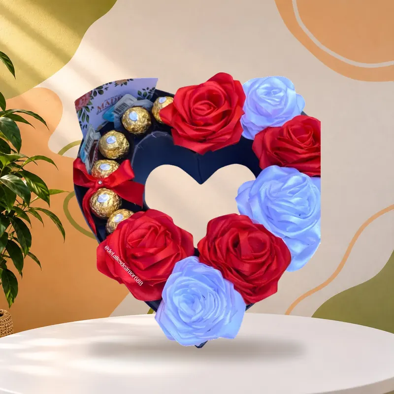 Rosas eternas artesanales en cinta de satín roja y blanca dentro de una caja en forma de corazón con bombones