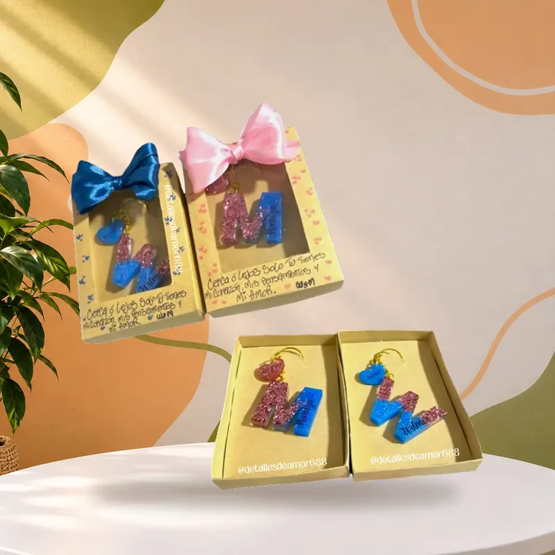 Cajas doradas con iniciales en resina y moño